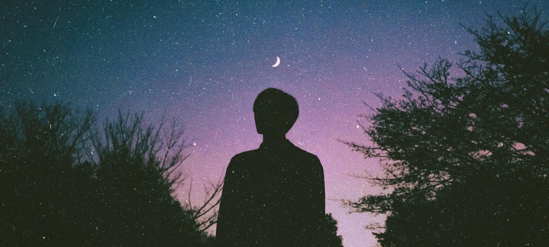 Person standing and reflecting on night sky full of stars