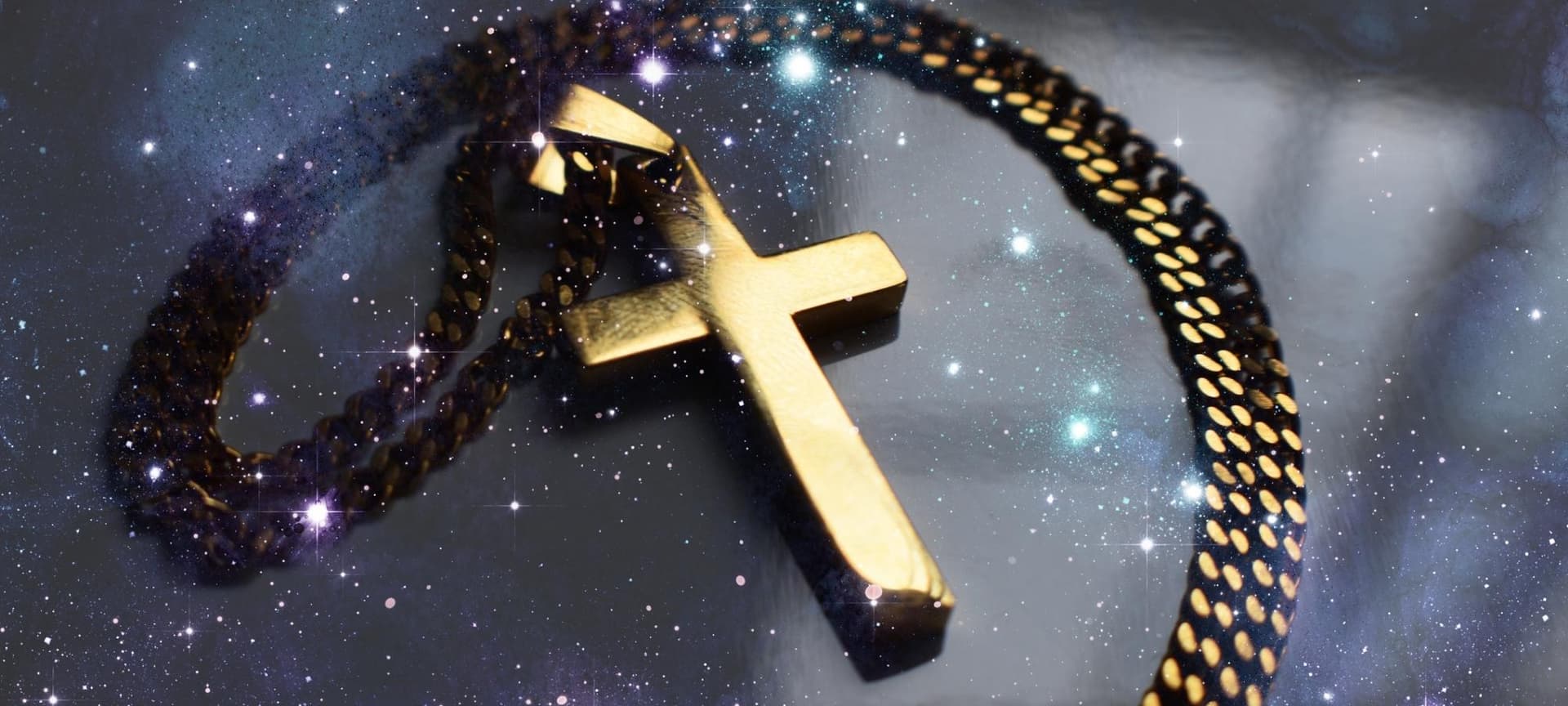 Gold cross necklace in front of starts and galaxies