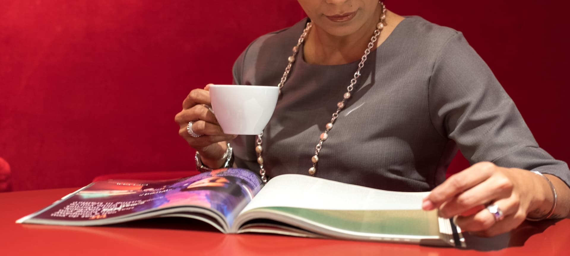 woman holding a cup and looking at a magazine