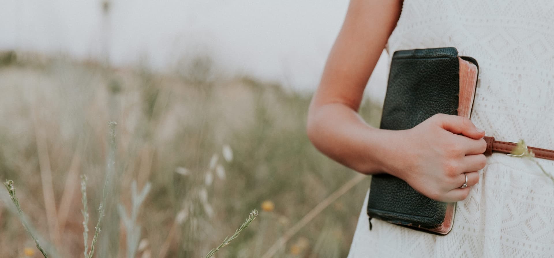 body standing in field holding bible