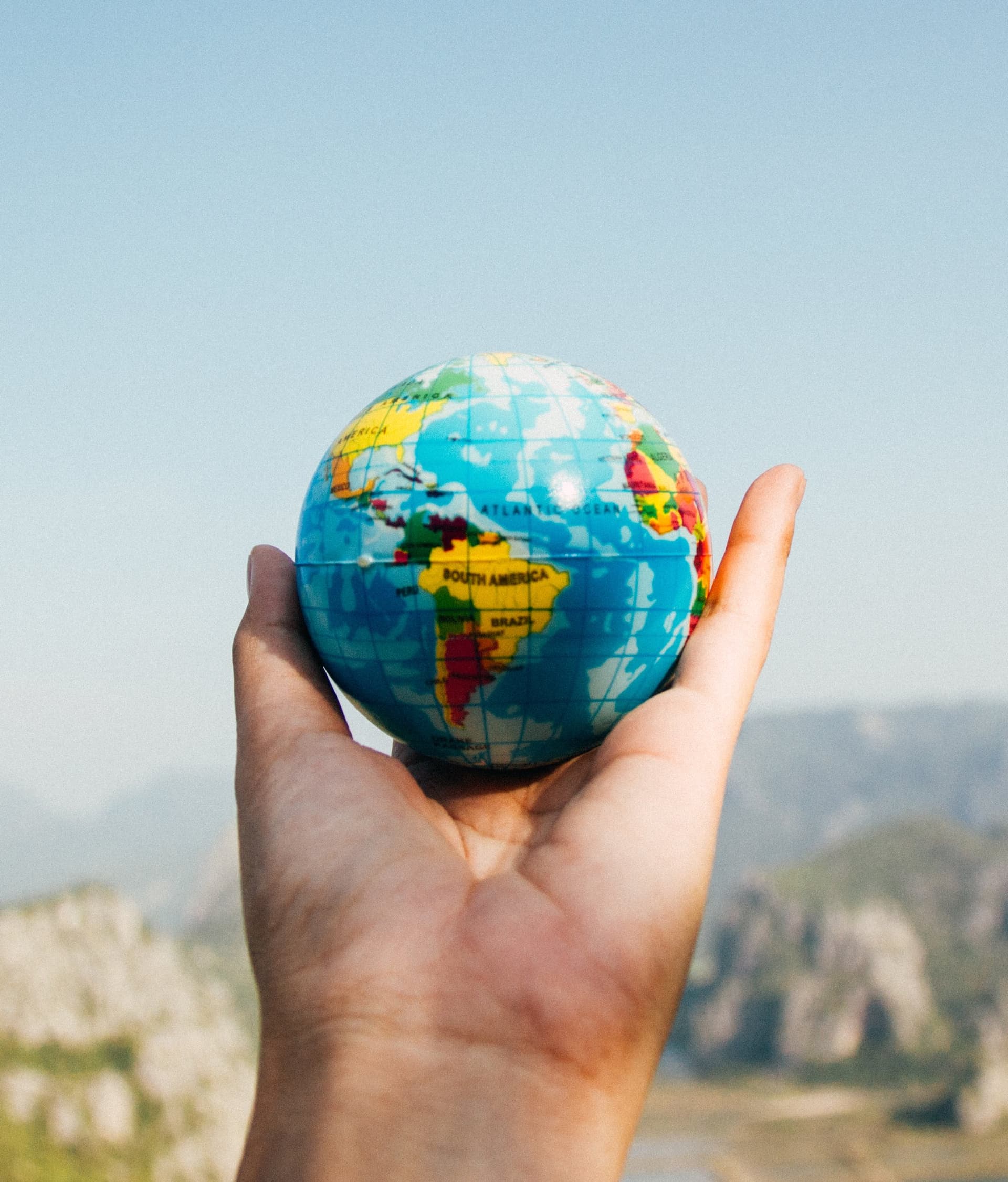 a hand holding a small globe