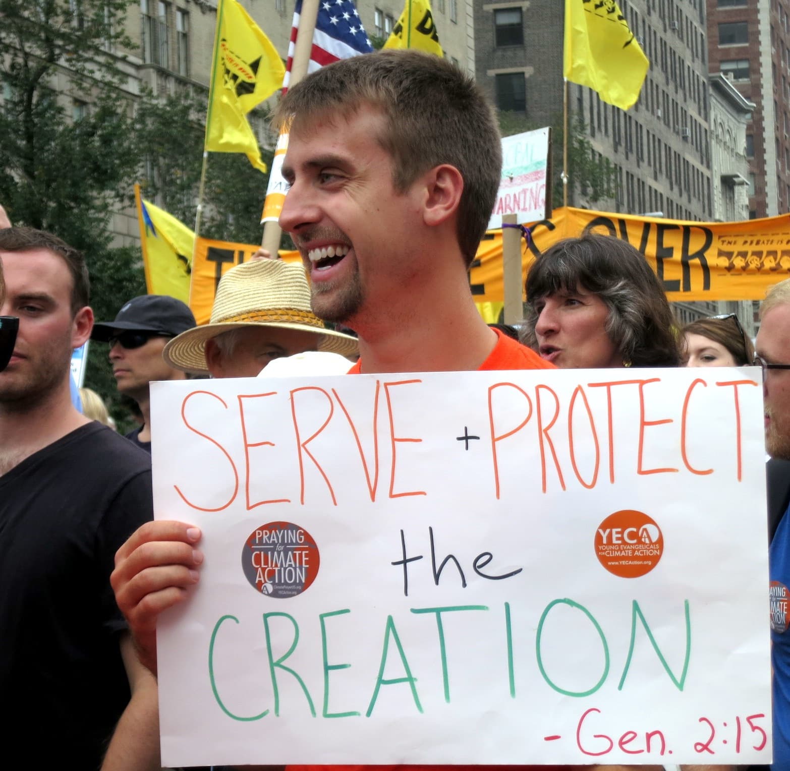 Man holding sign reading "serve and protect the creation, Gen. 2:15"