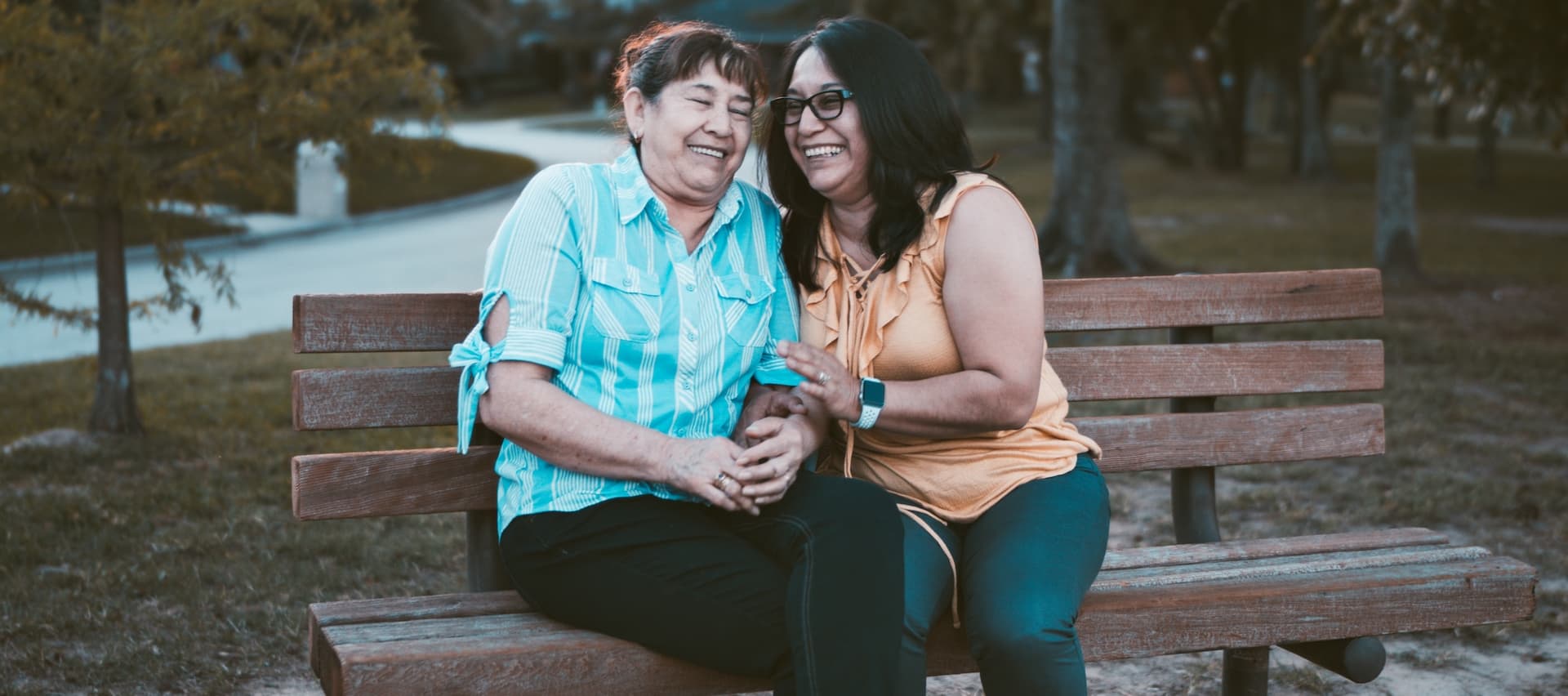 two women laughing on a bench