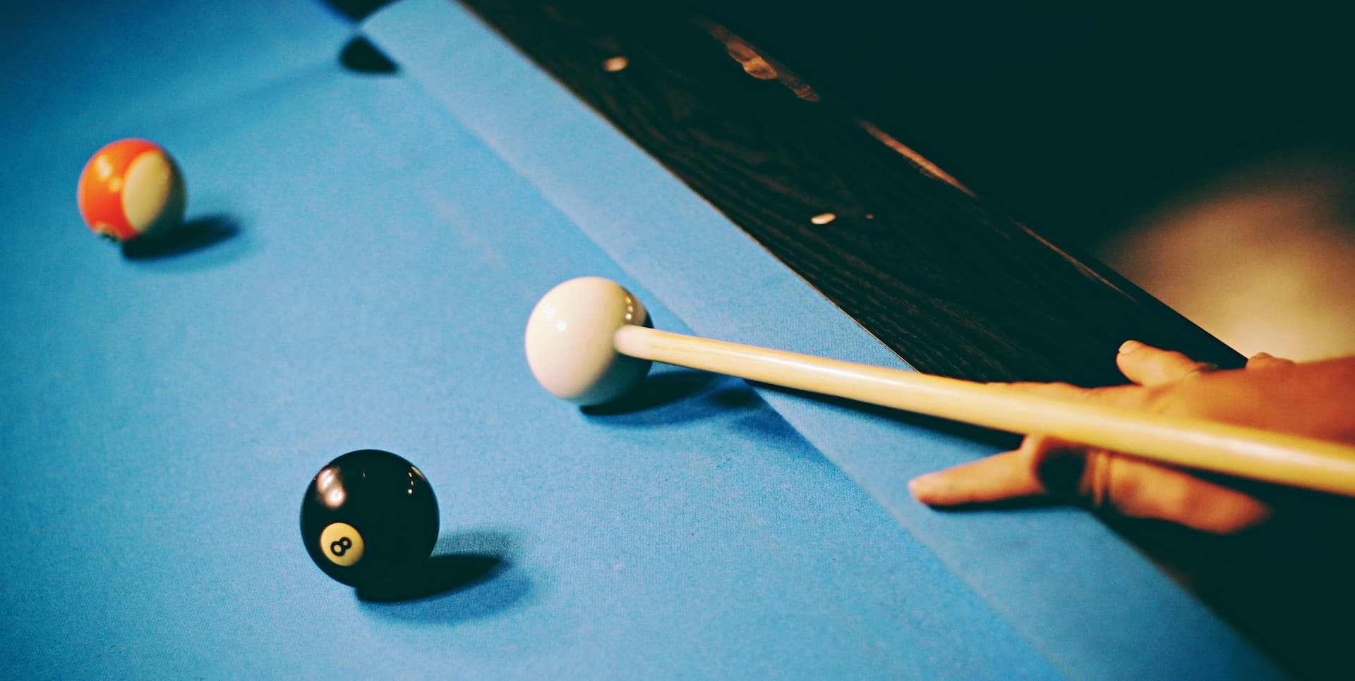 a hand shooting a cue ball on a billiards table