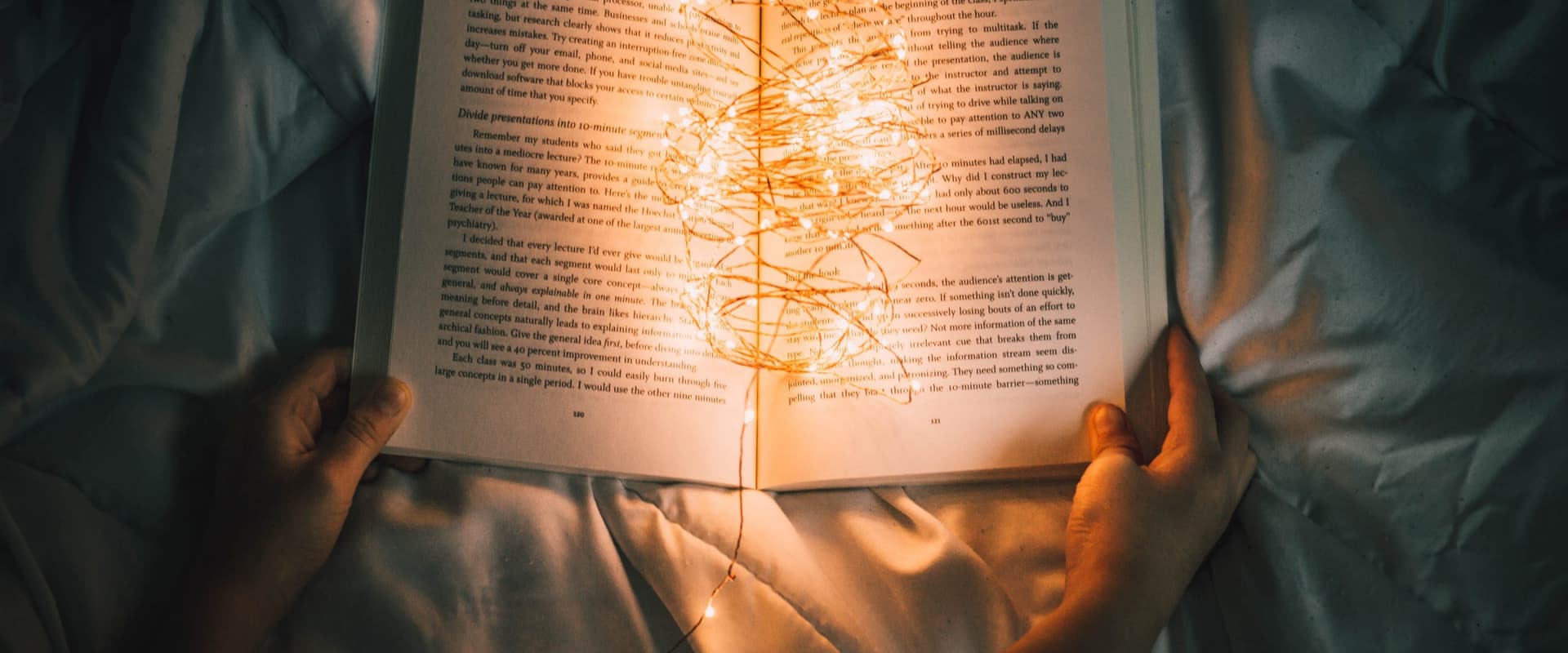 book on bed with string of lights