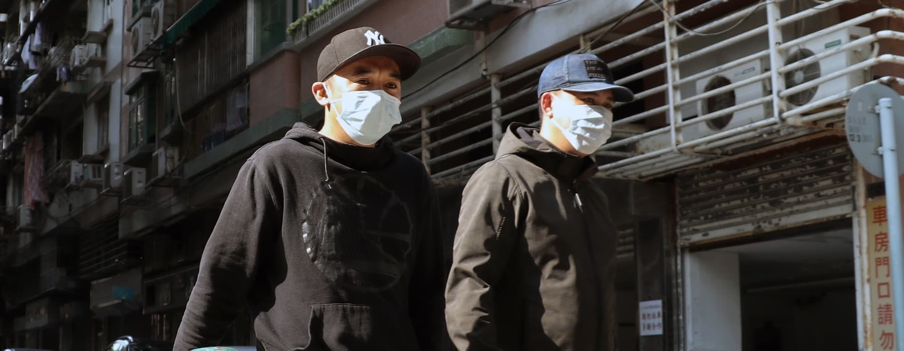 2 men in surgical masks walking in the street