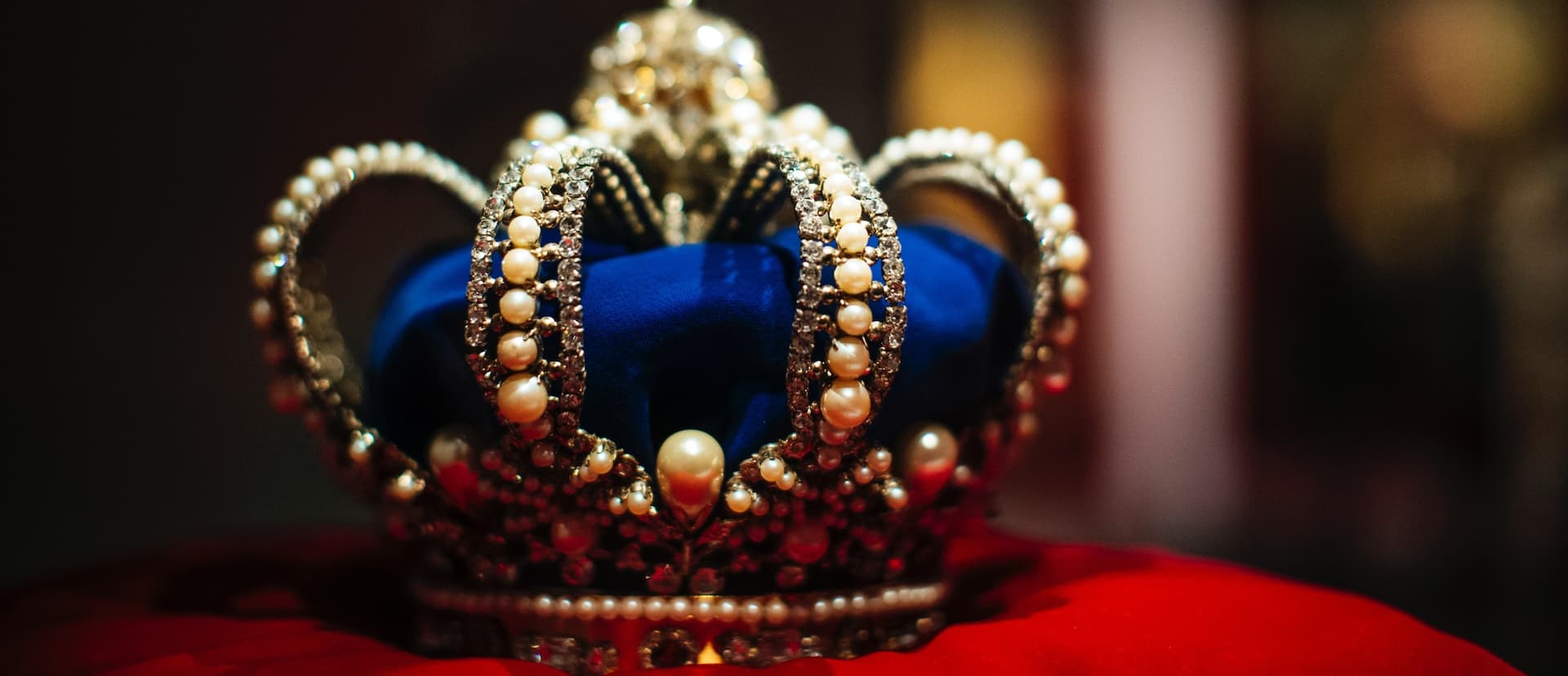 blue and gold crown sitting on a red cushion