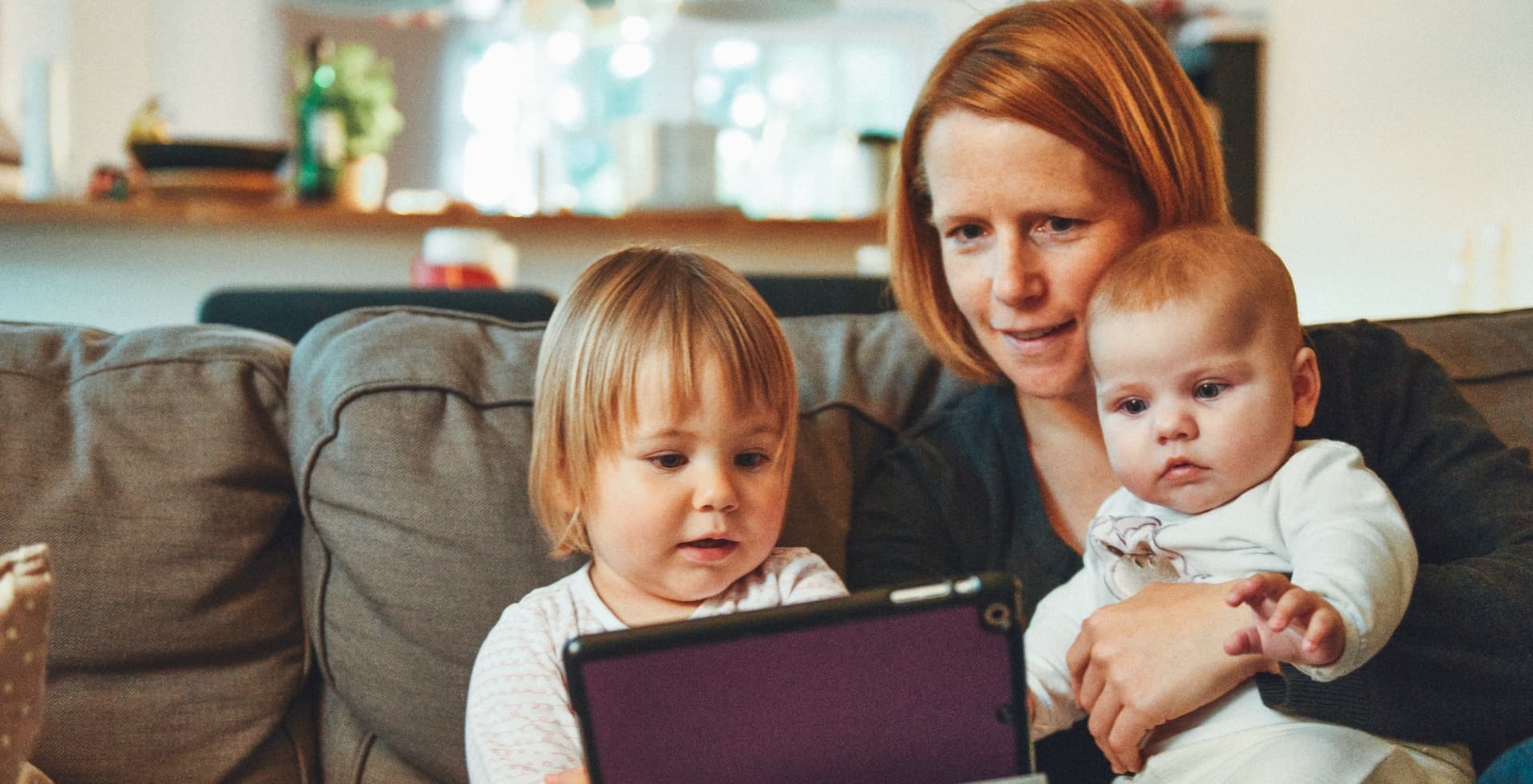 mom and kids with a tablet sitting on a couch