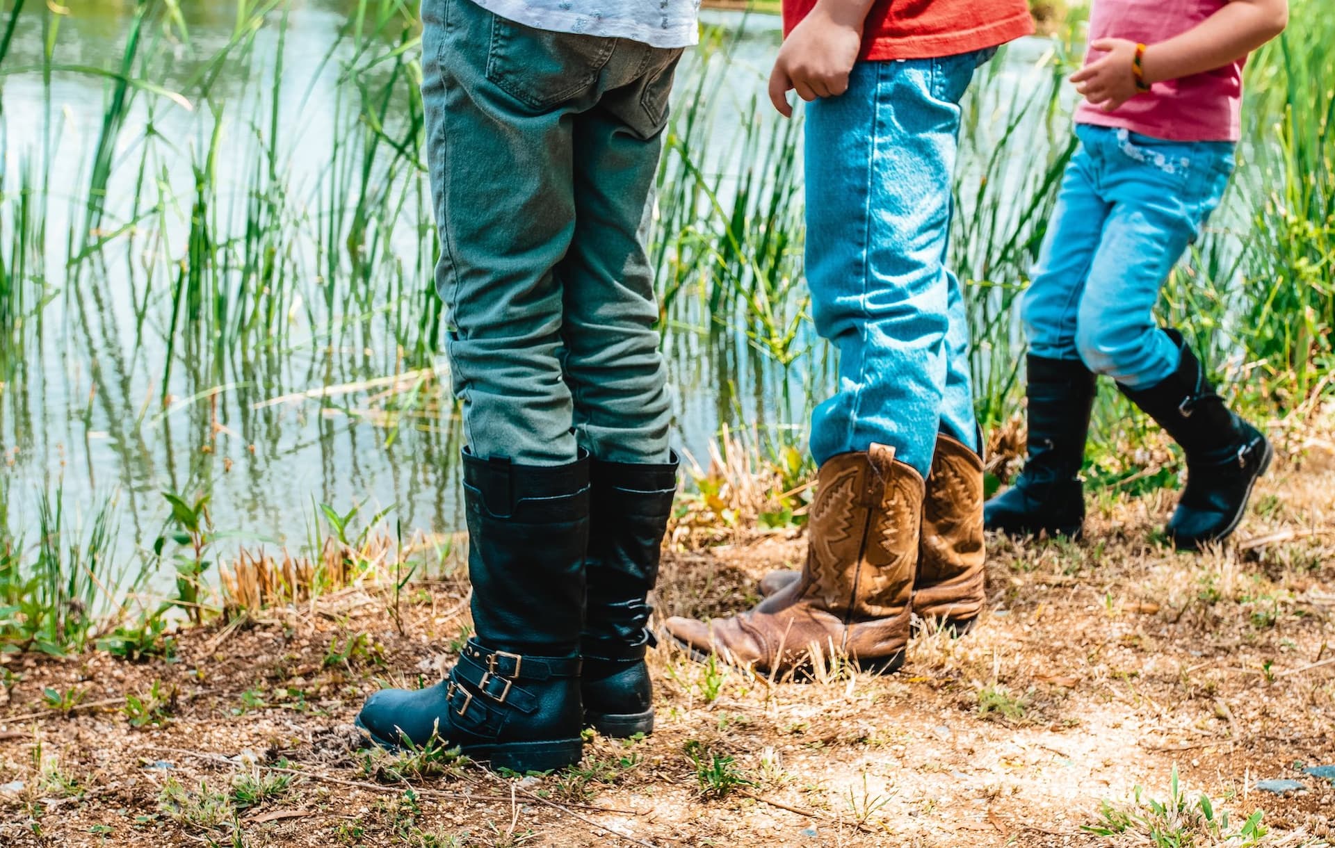 three people standing in boots by a riverbank