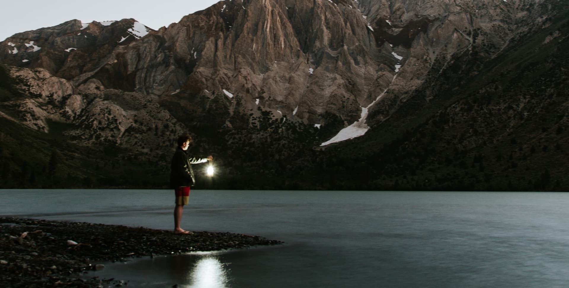 man holding lantern by a lake