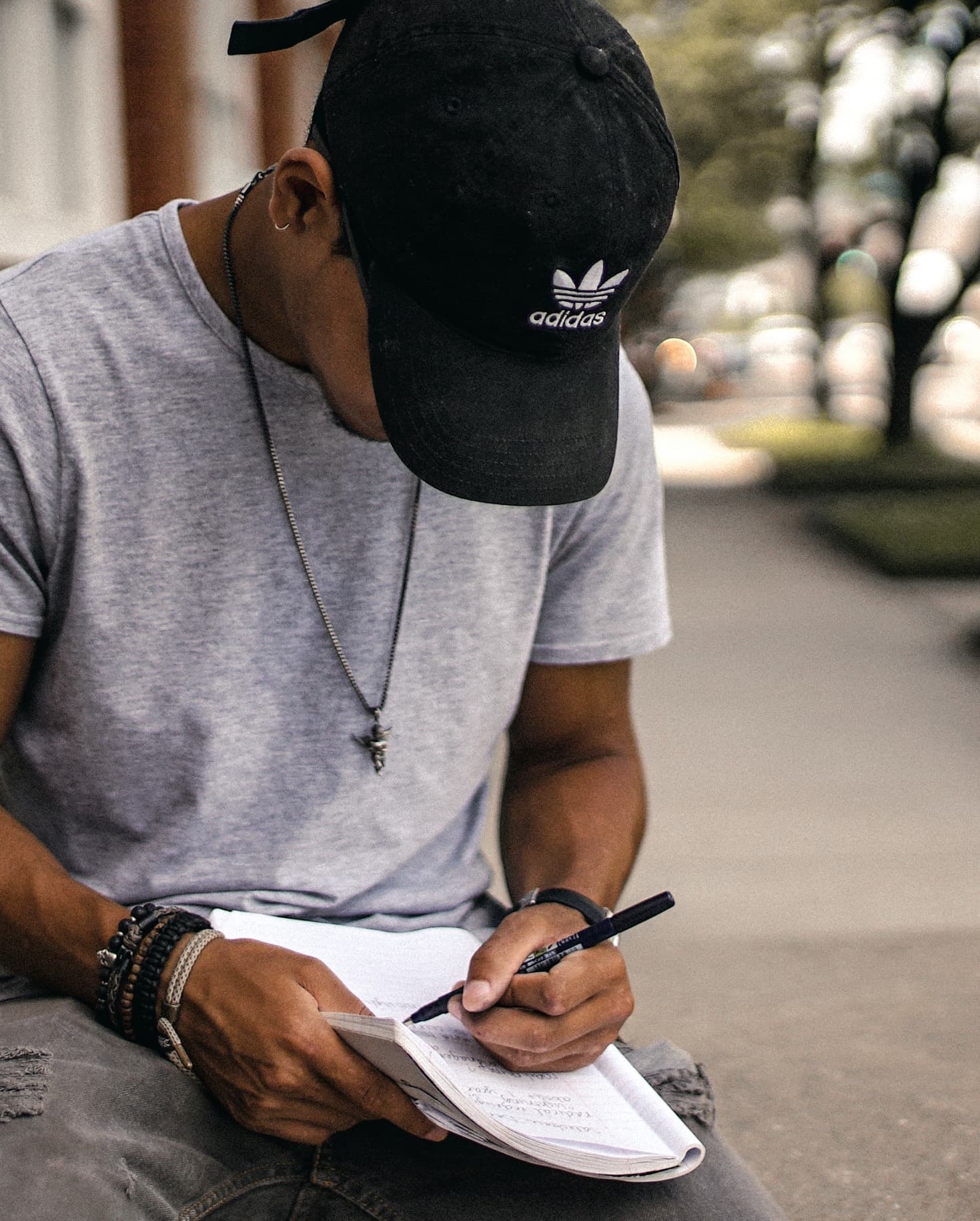 man in a baseball hat writing in a notebook
