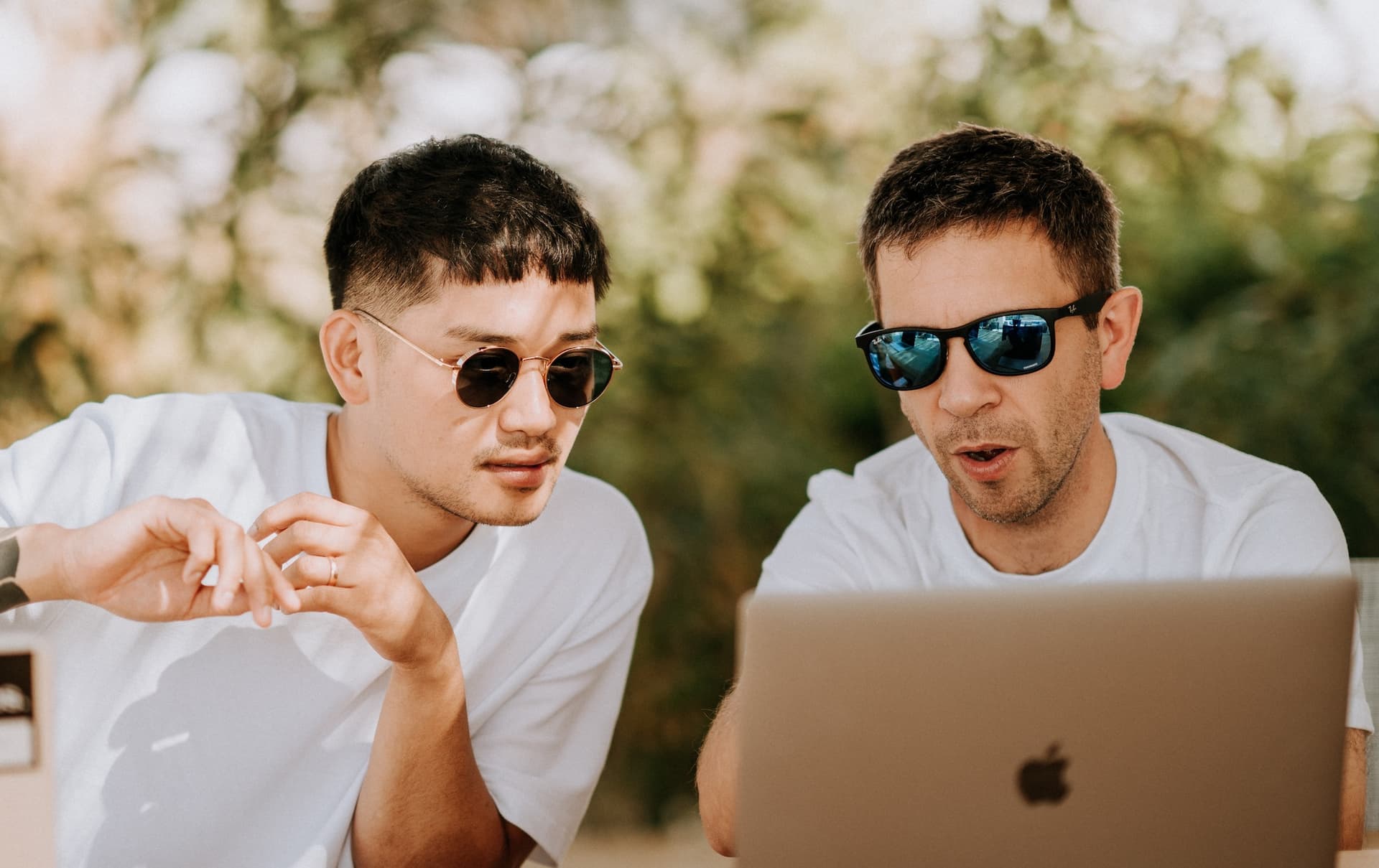 two men in sunglasses looking at a computer