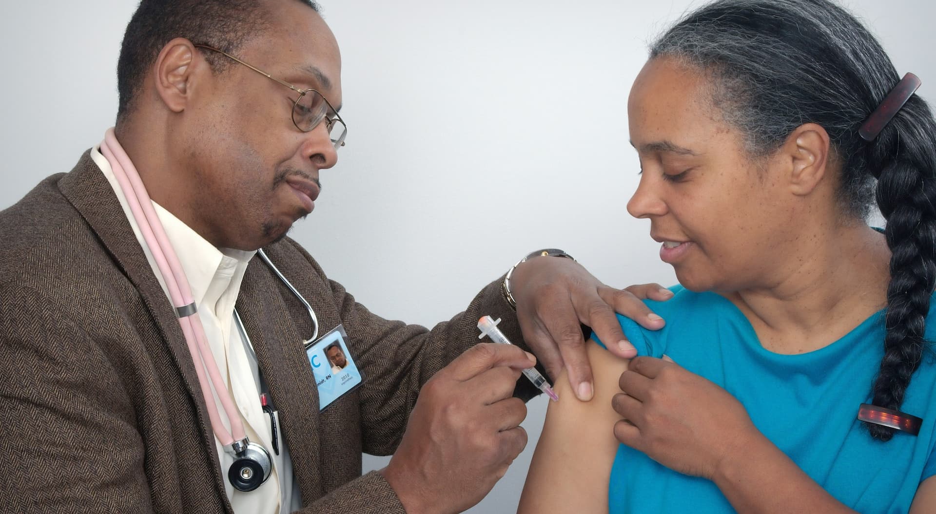 a man administers a vaccine into a woman's arm