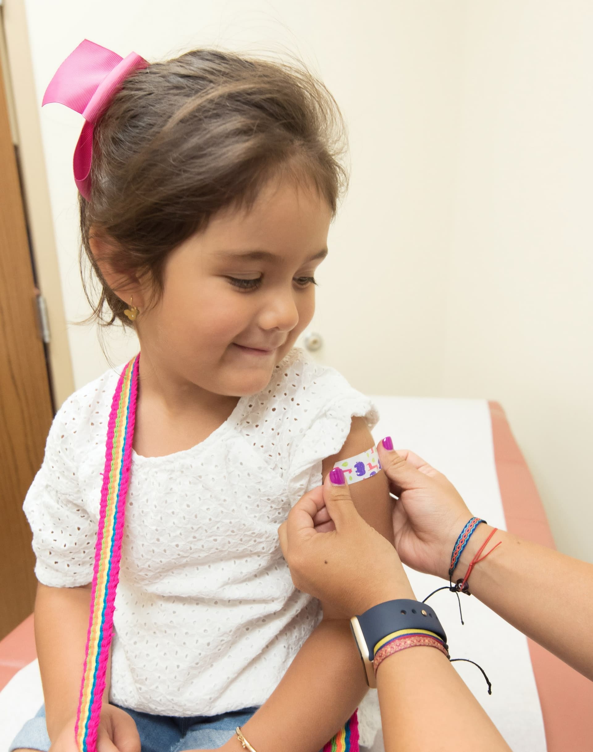 young girl getting a bandage on her arm after a vaccine