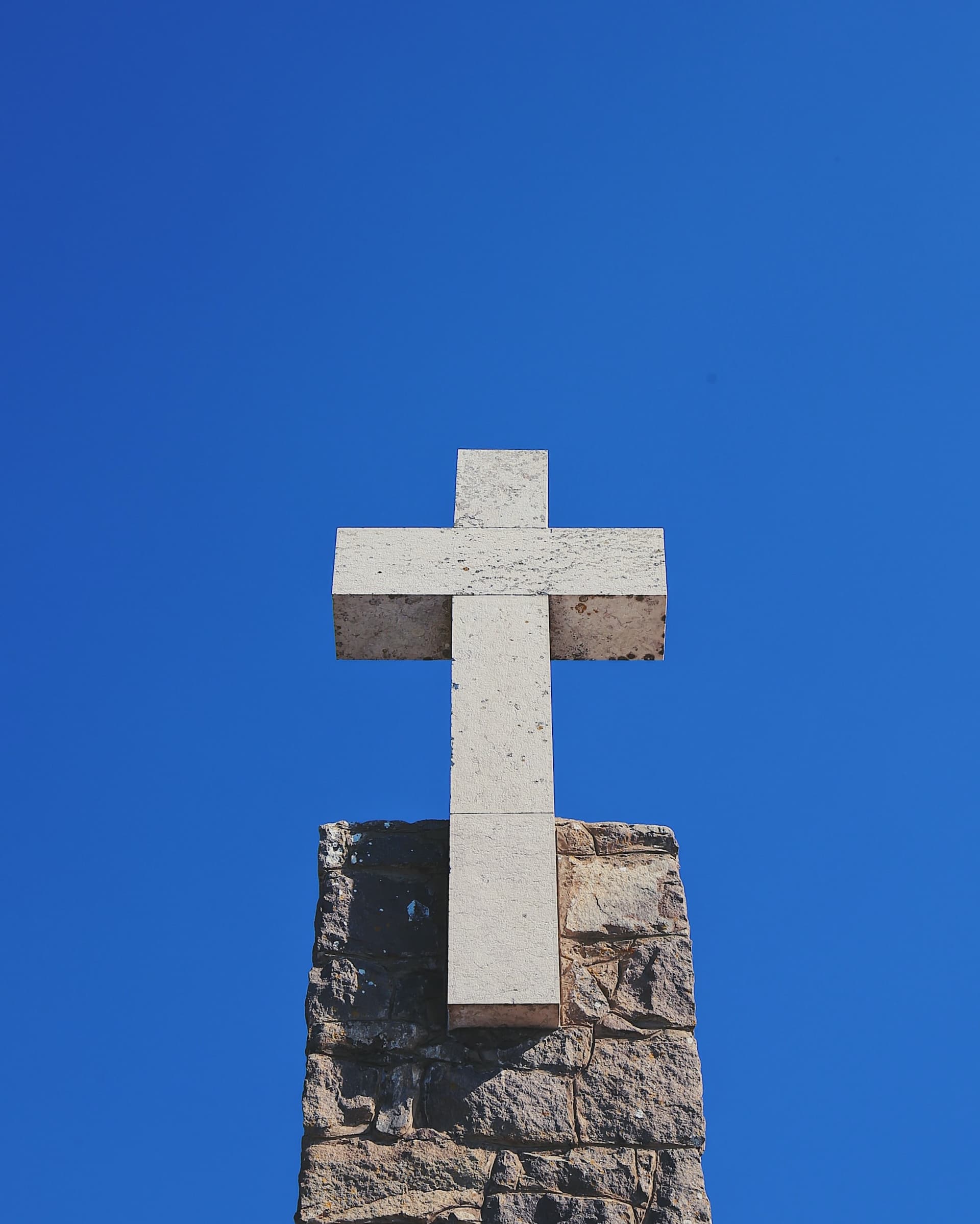 white cross mounted on stone chimney
