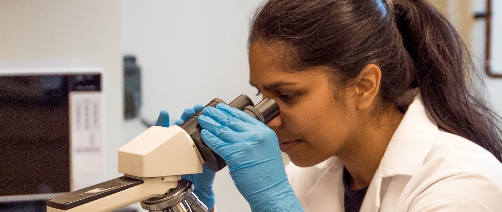woman looking through a microscope