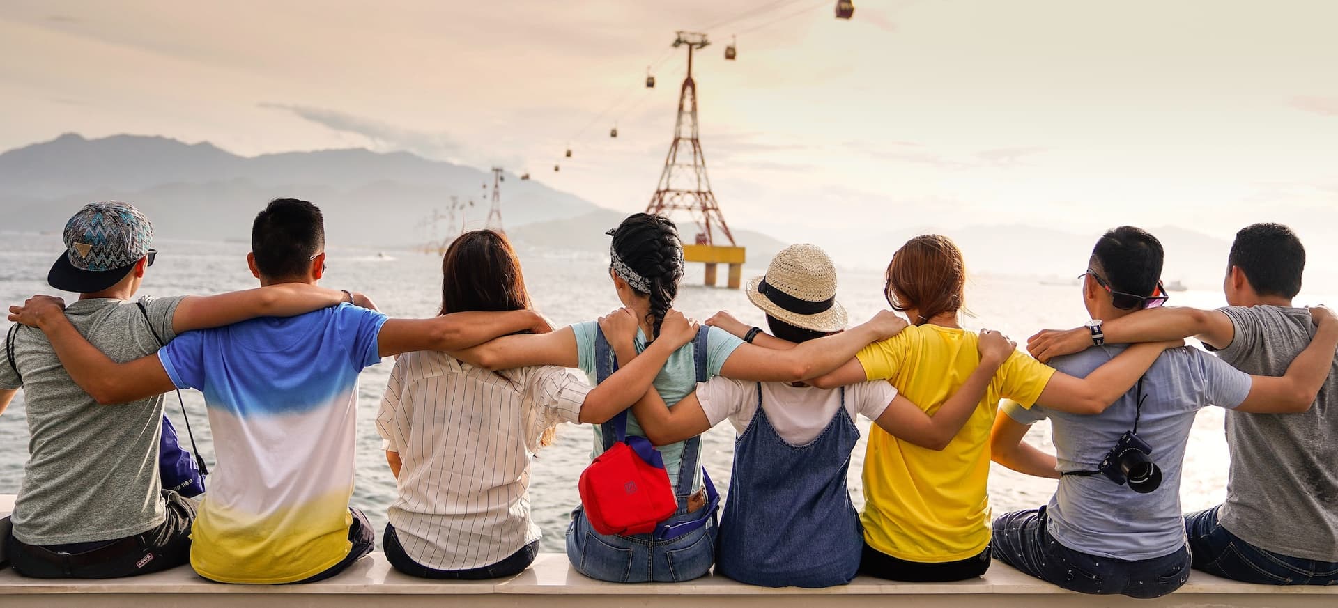 eight people sitting on a pier with their arms around each other's shoulders