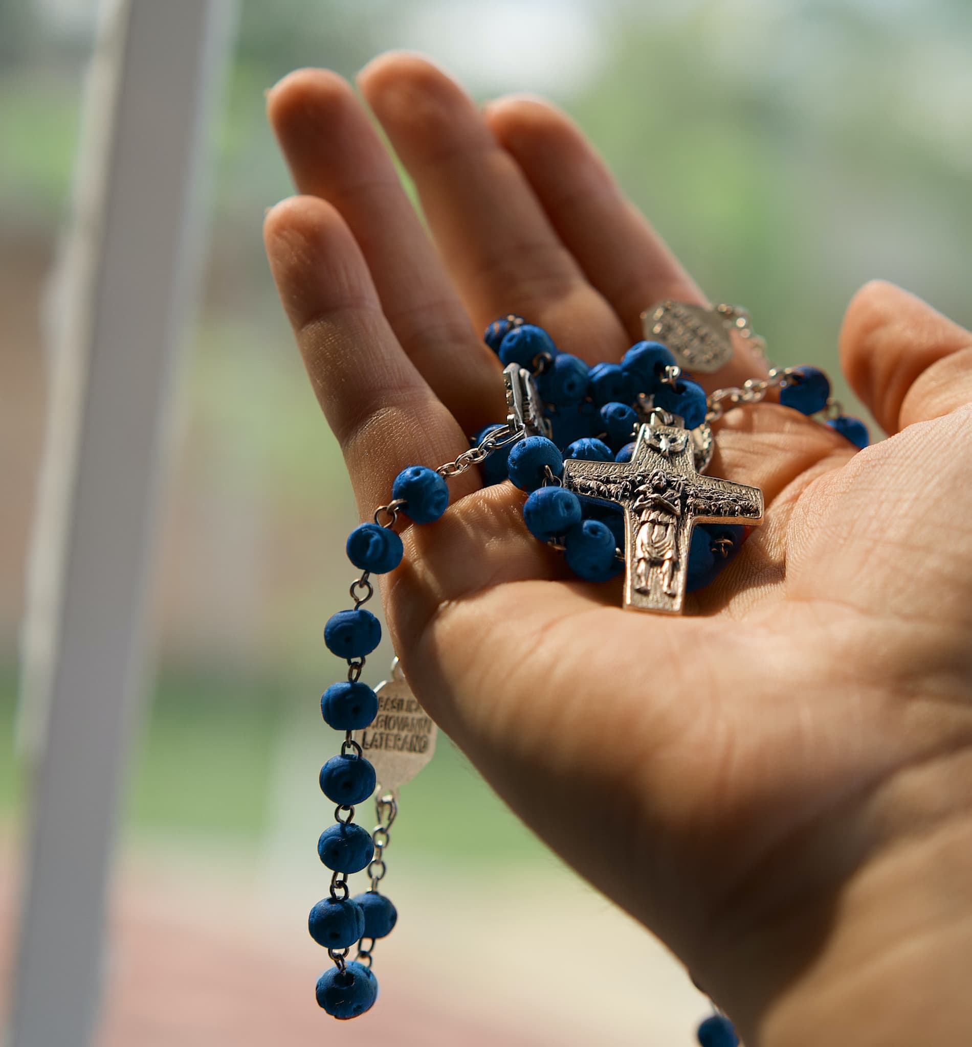 hand holding blue rosary