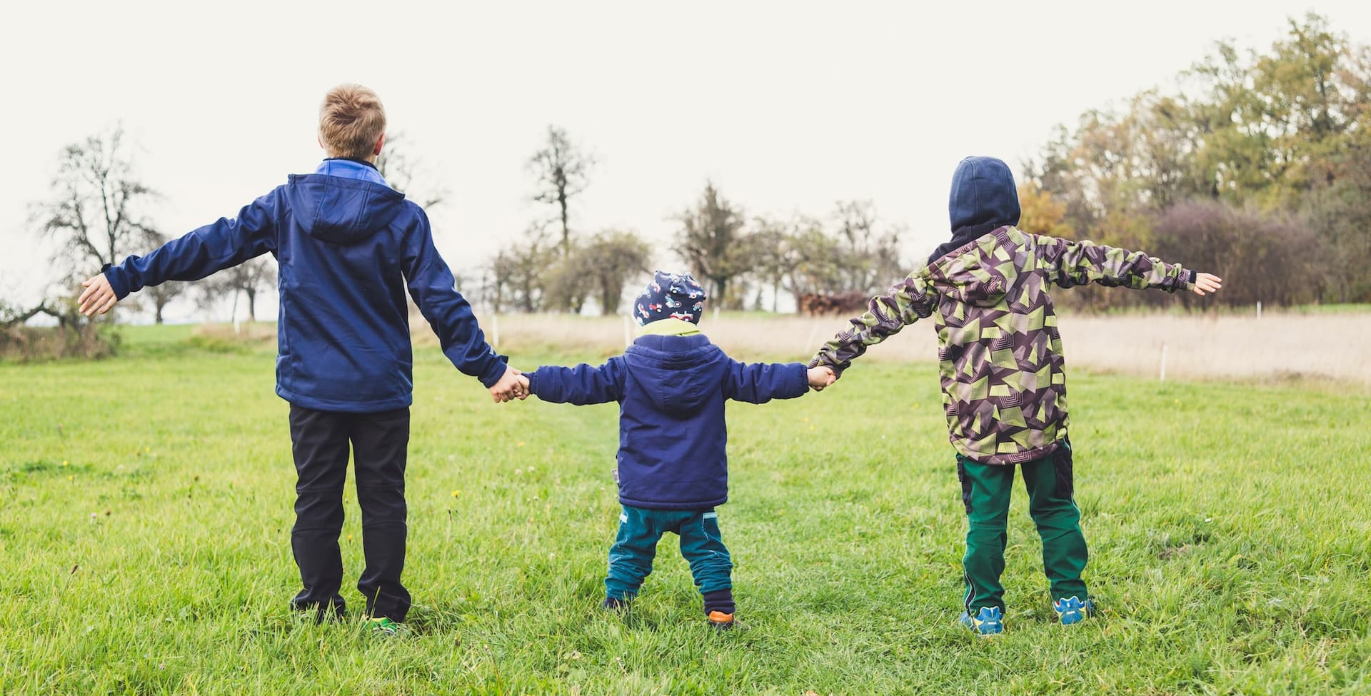 the backs of three kids holding hands