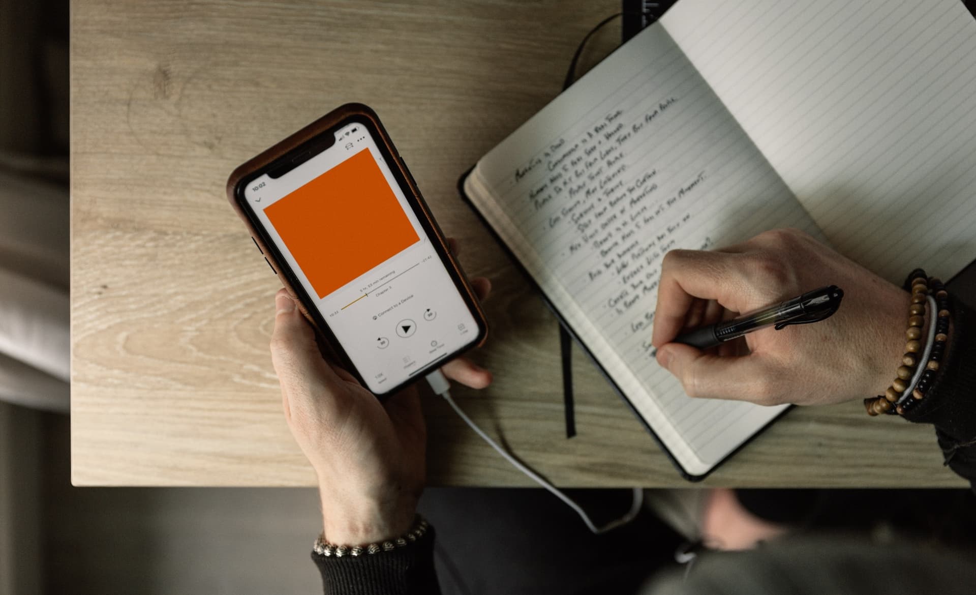 person taking notes while listening to a phone