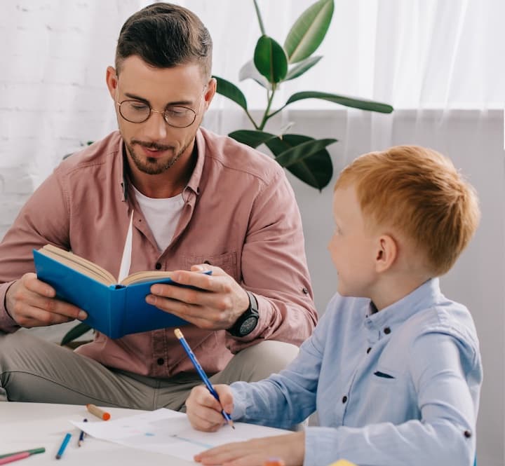 dad reading book to child at a table