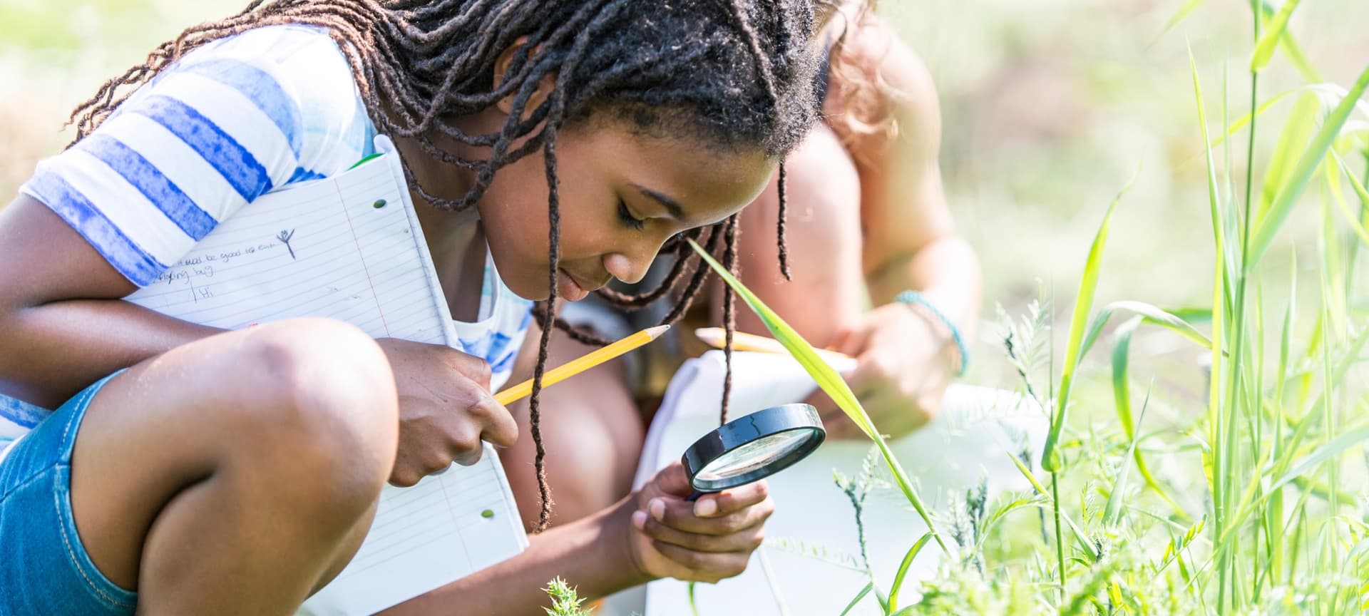 Young girl uses a magnifying glass to study plants