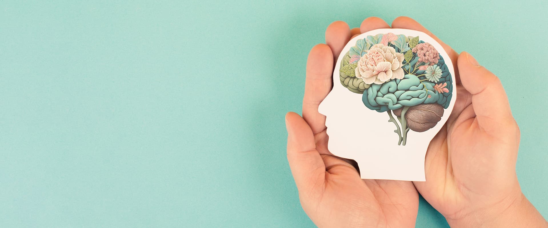 Paper cut out of head with brain made of flowers on green background