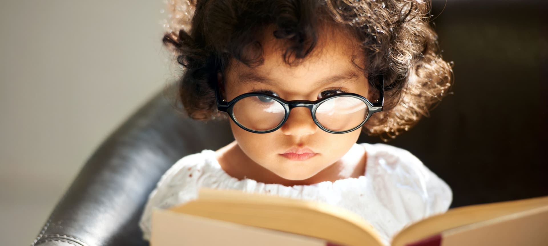 A child wearing glasses reads a book