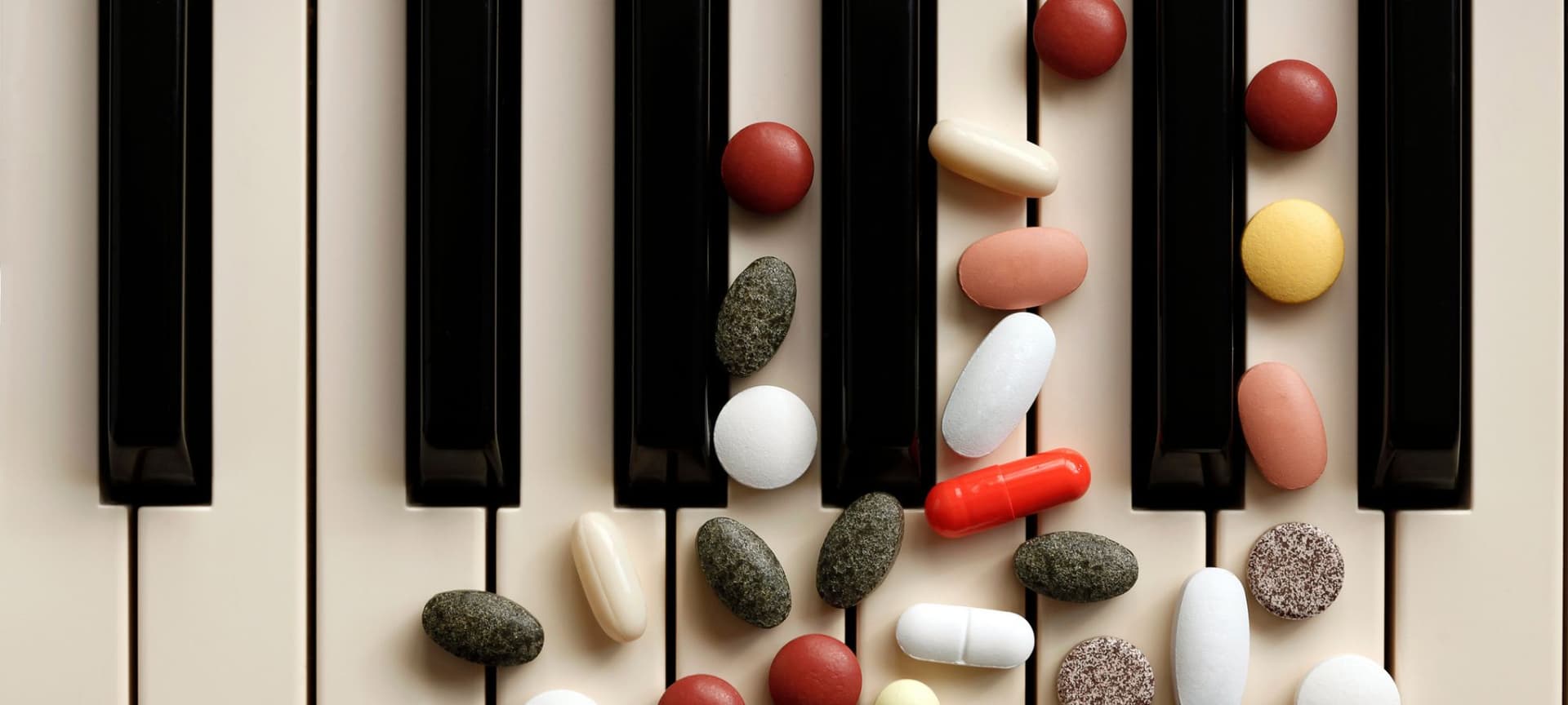 Close-up of piano keys with pills and supplements on it.