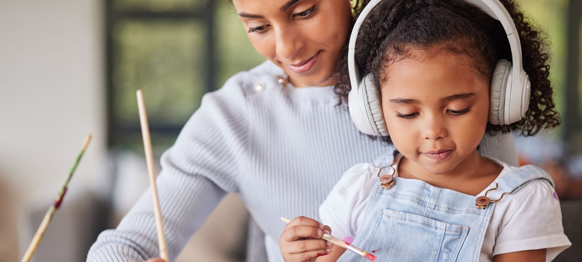 Mom and child painting together. Child is wearing noise cancelling headphones
