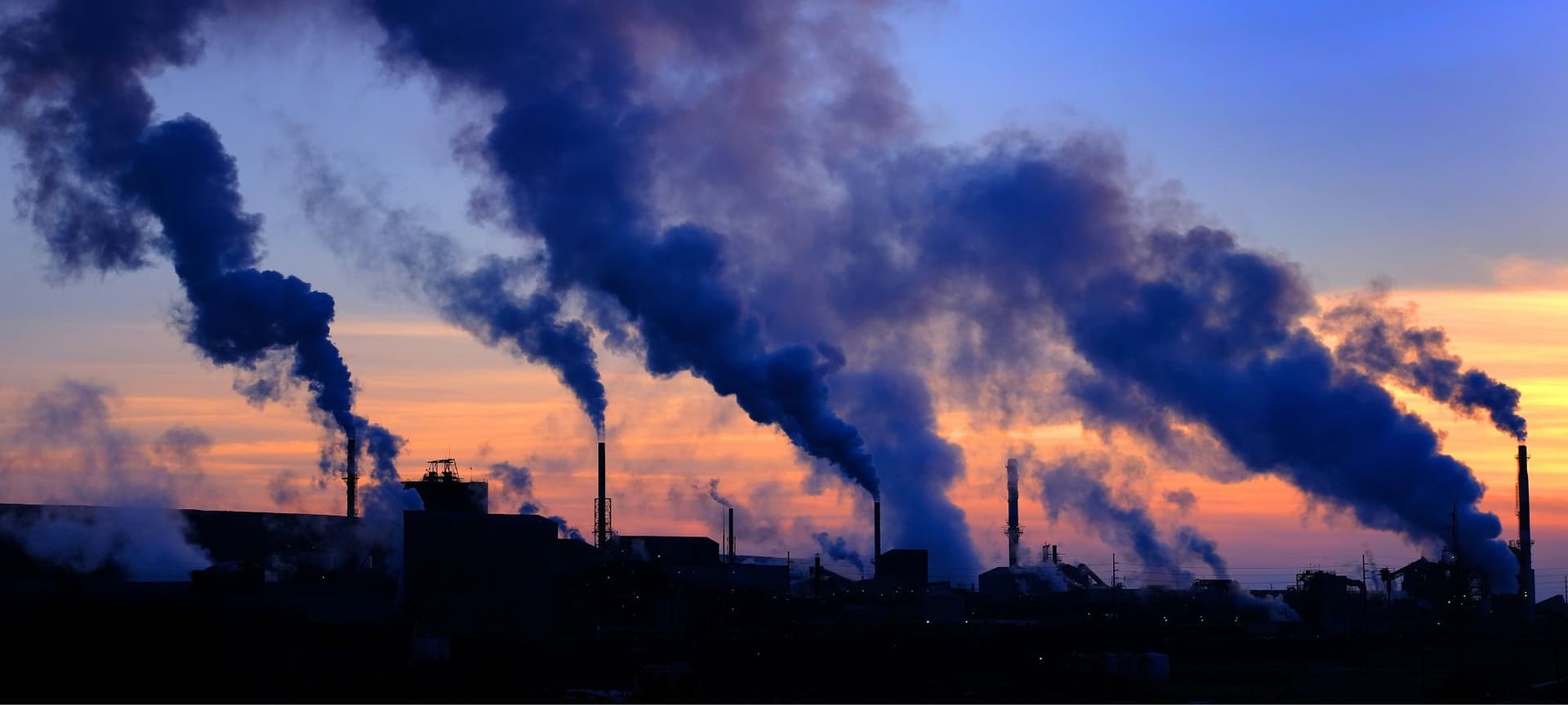 Profuse smoke from a pollution plant filling the sky during sundown.
