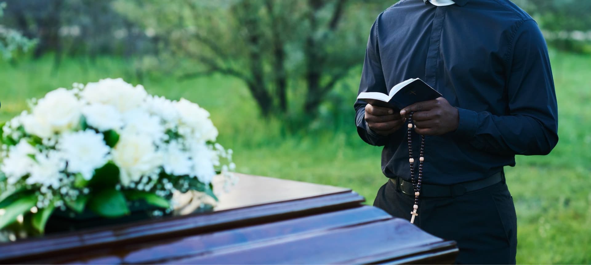 Minister reading funeral rights at cemetary in front of casket