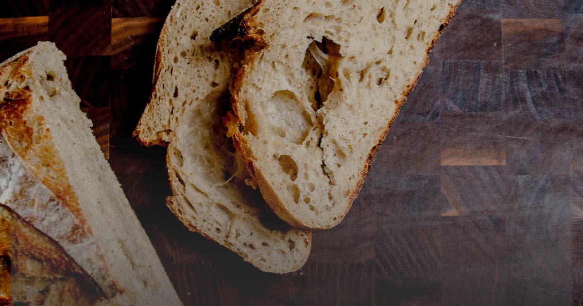 A loaf of bread with some cut slices in front