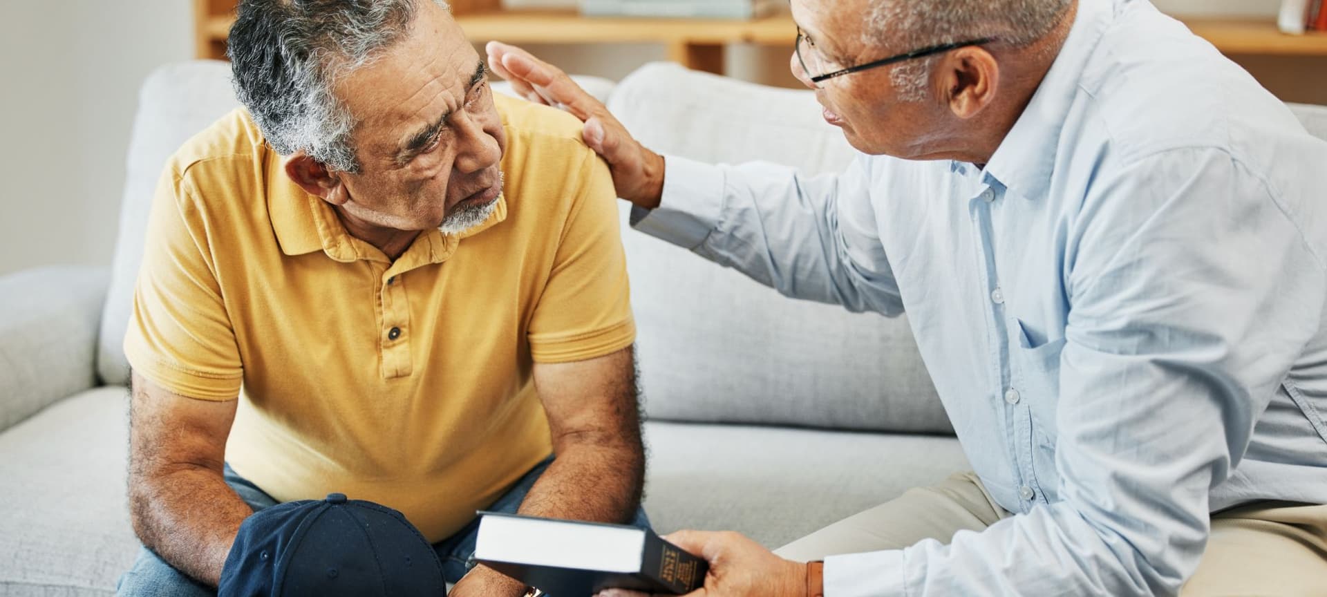 Pastor counseling church member, holding bible and comforting him with hand on back