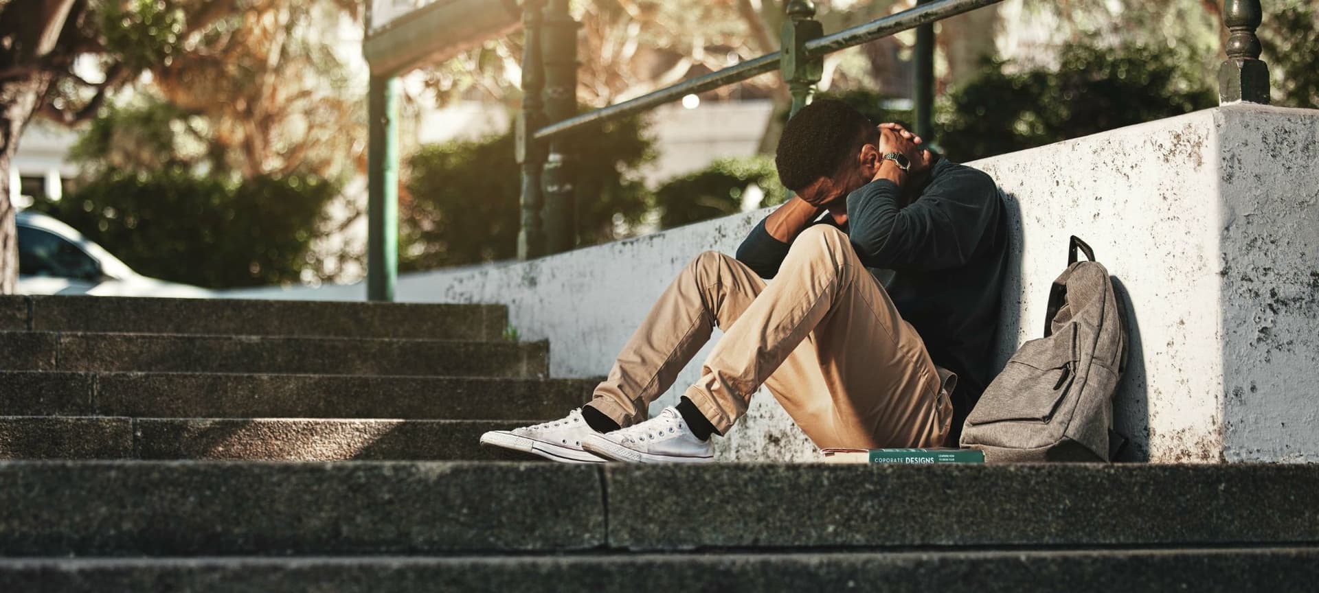 A person sitting on steps hunched over with arms on head