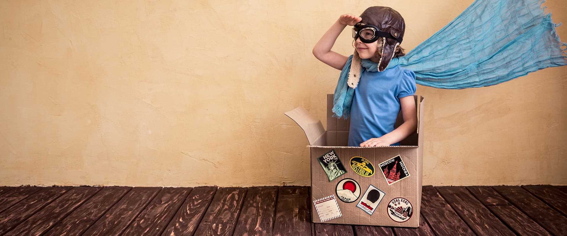 boy dressed as adventurer sitting in cardboard box