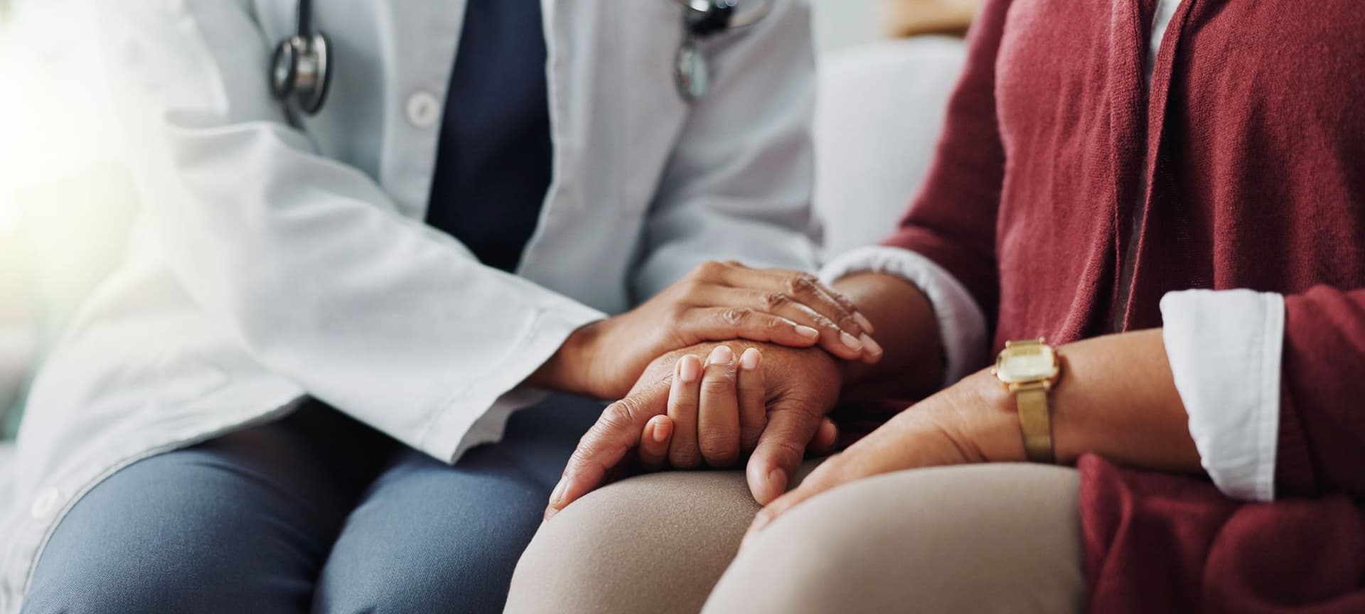 A closeup of a medical doctor's hands embracing a patients hands.