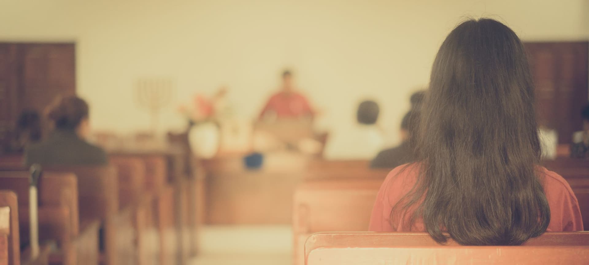 Back view of a congregational member sitting in a pew in a church