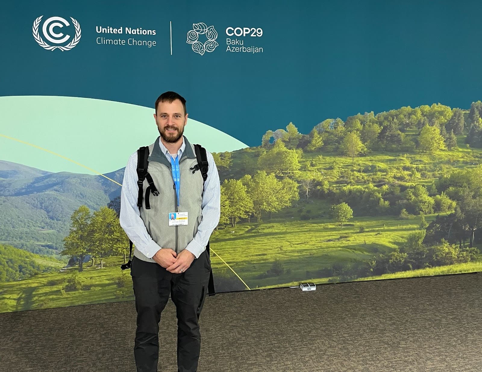 Article author Colin at COP29. Colin stands in front of a backdrop depicting grass and trees. Text on the backdrop reads "United Nations Climate Change" and "COP29 Baku Azerbaijan."