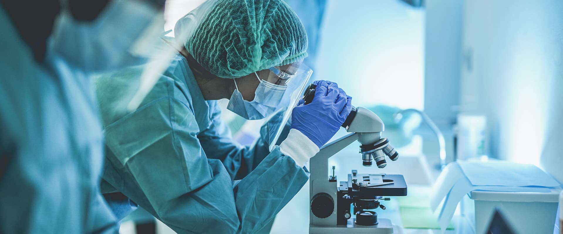Person in lab looking through microscope