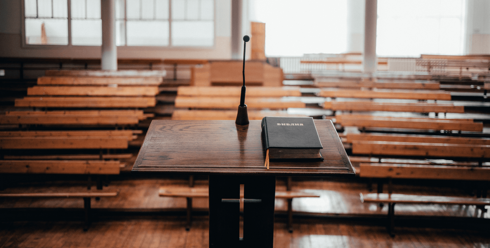 Image of an empty church taken from the pulpit. A Bible sits on the pulpit.