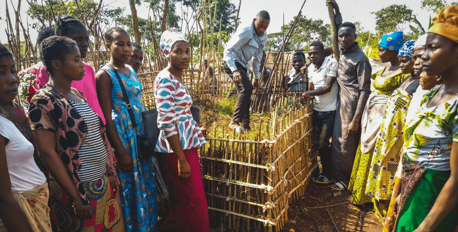 A group of people participate in one of Plant With Purpose's farmer field schools. The people stand around a compost bin.