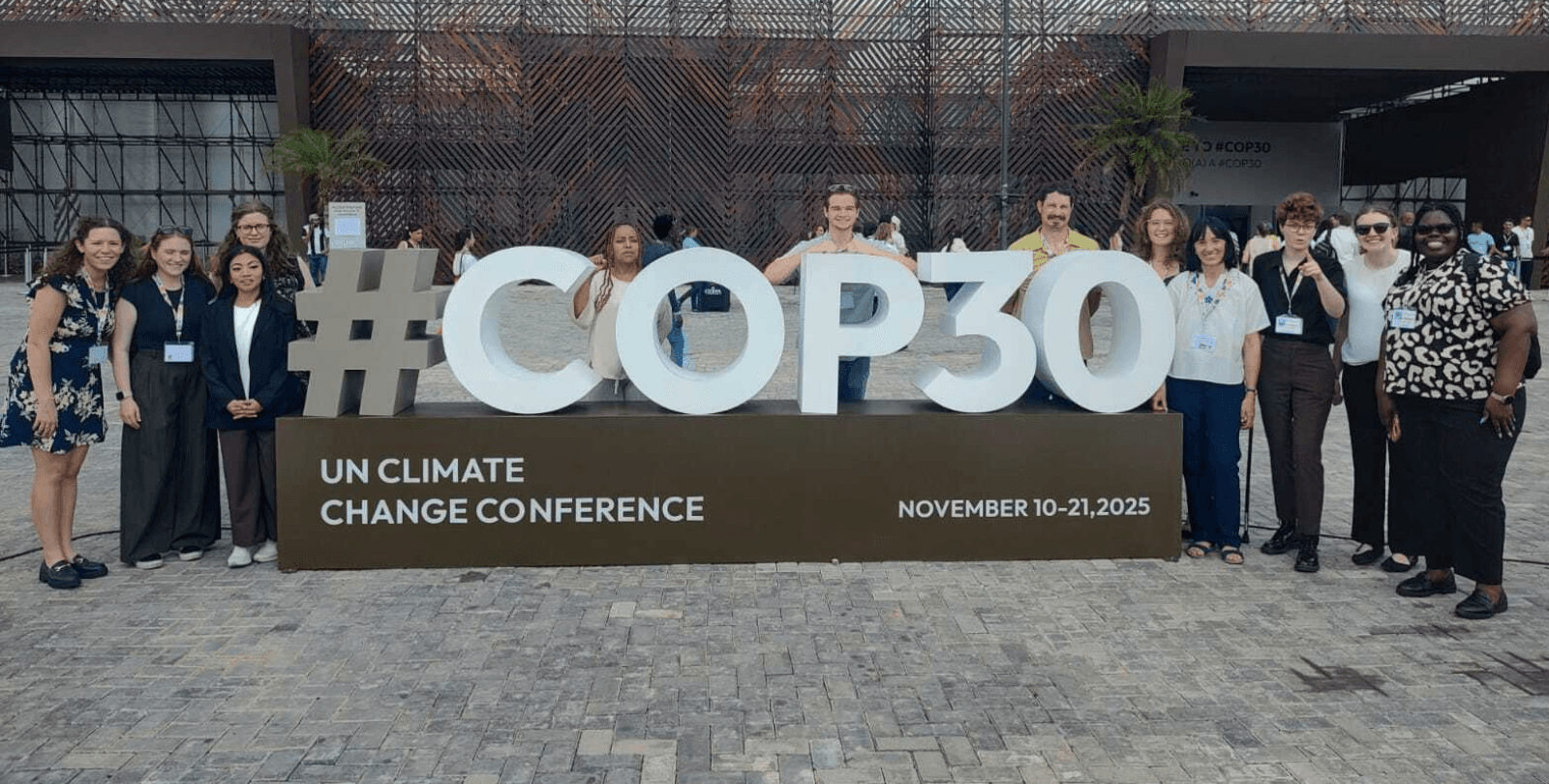 Twelve members of CCOP stand around big blocks that read "COP30".