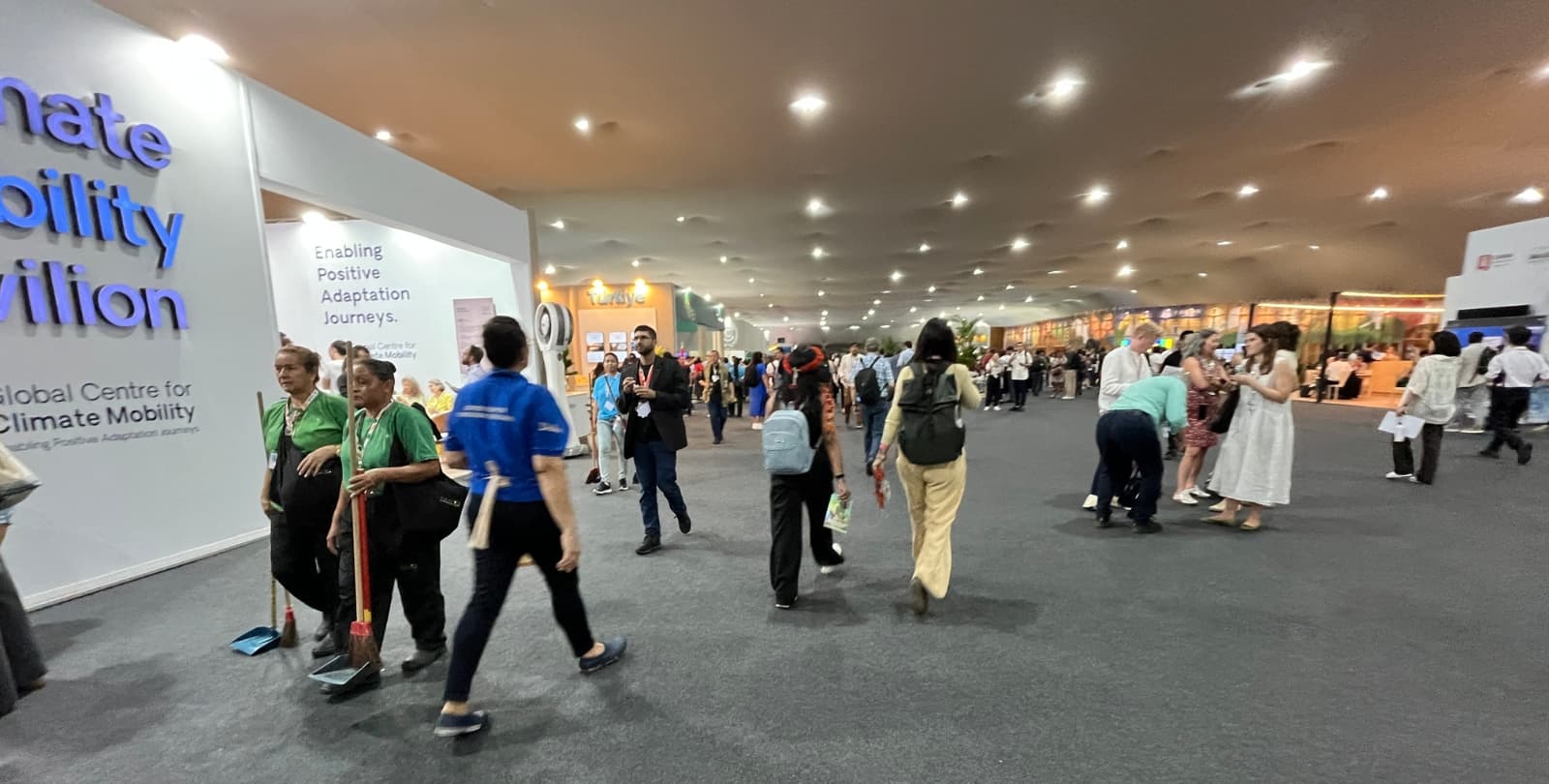 Photo of a concourse at COP30. Groups of people walk around the conference floor.