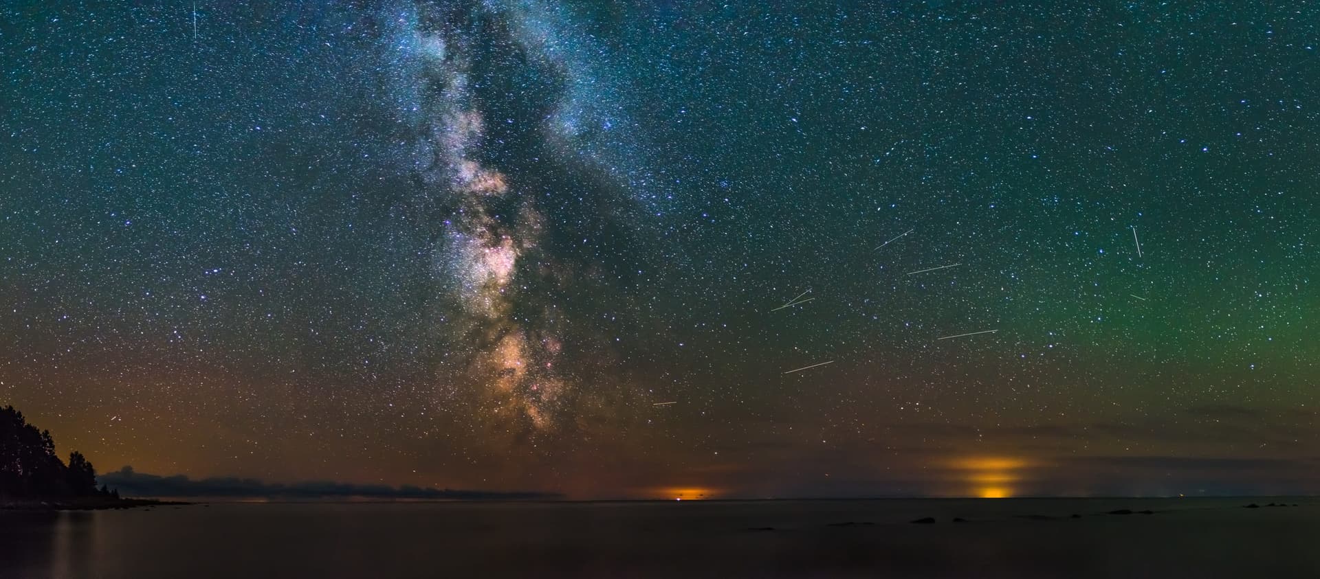 The Milky Way galaxy, as seen from the coast of Estonia. Thousands of stars shine above a body of water.