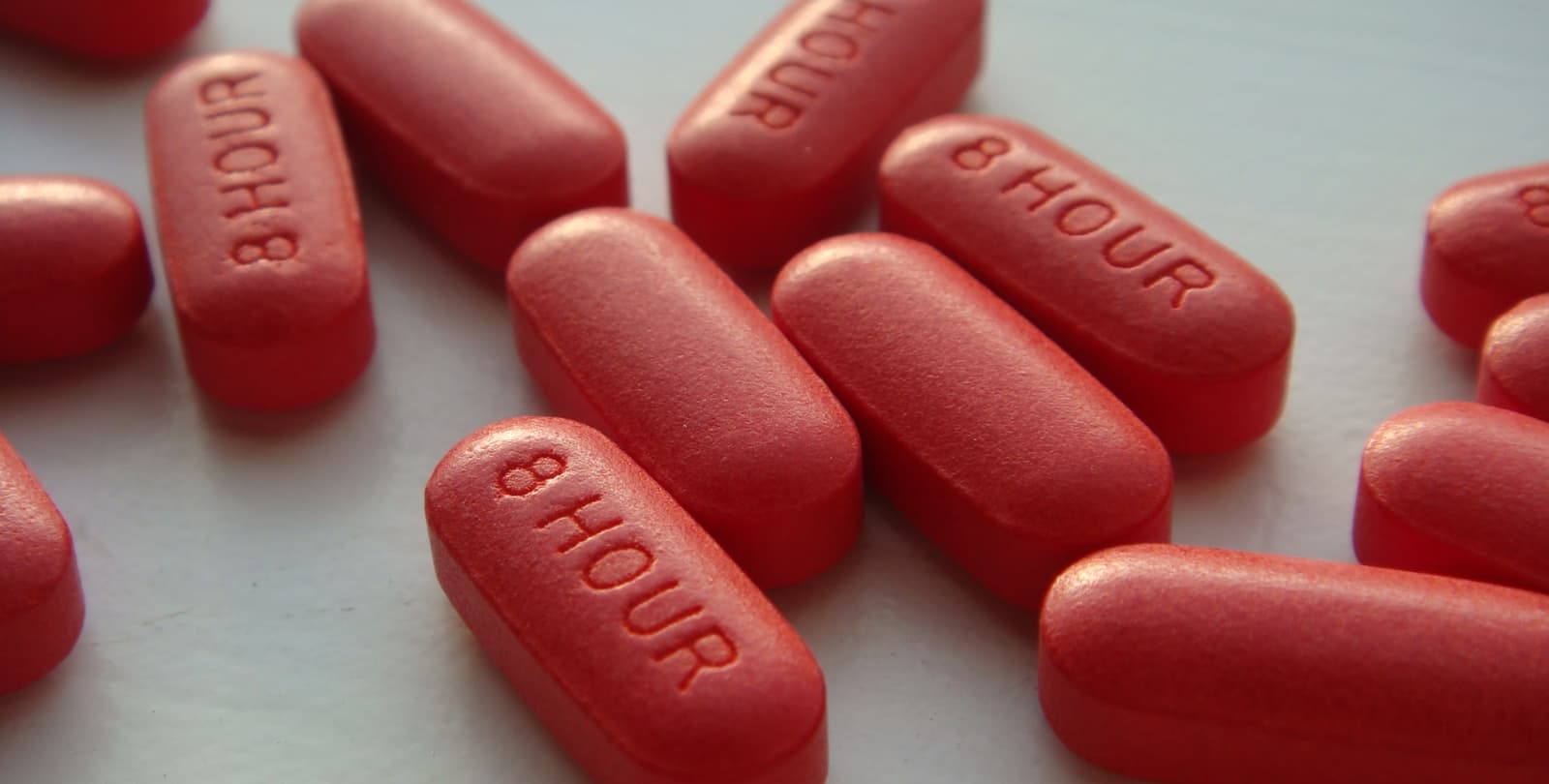 Close-up photo of a pile of Tylenol pills. Pills say "8 hour" on them.