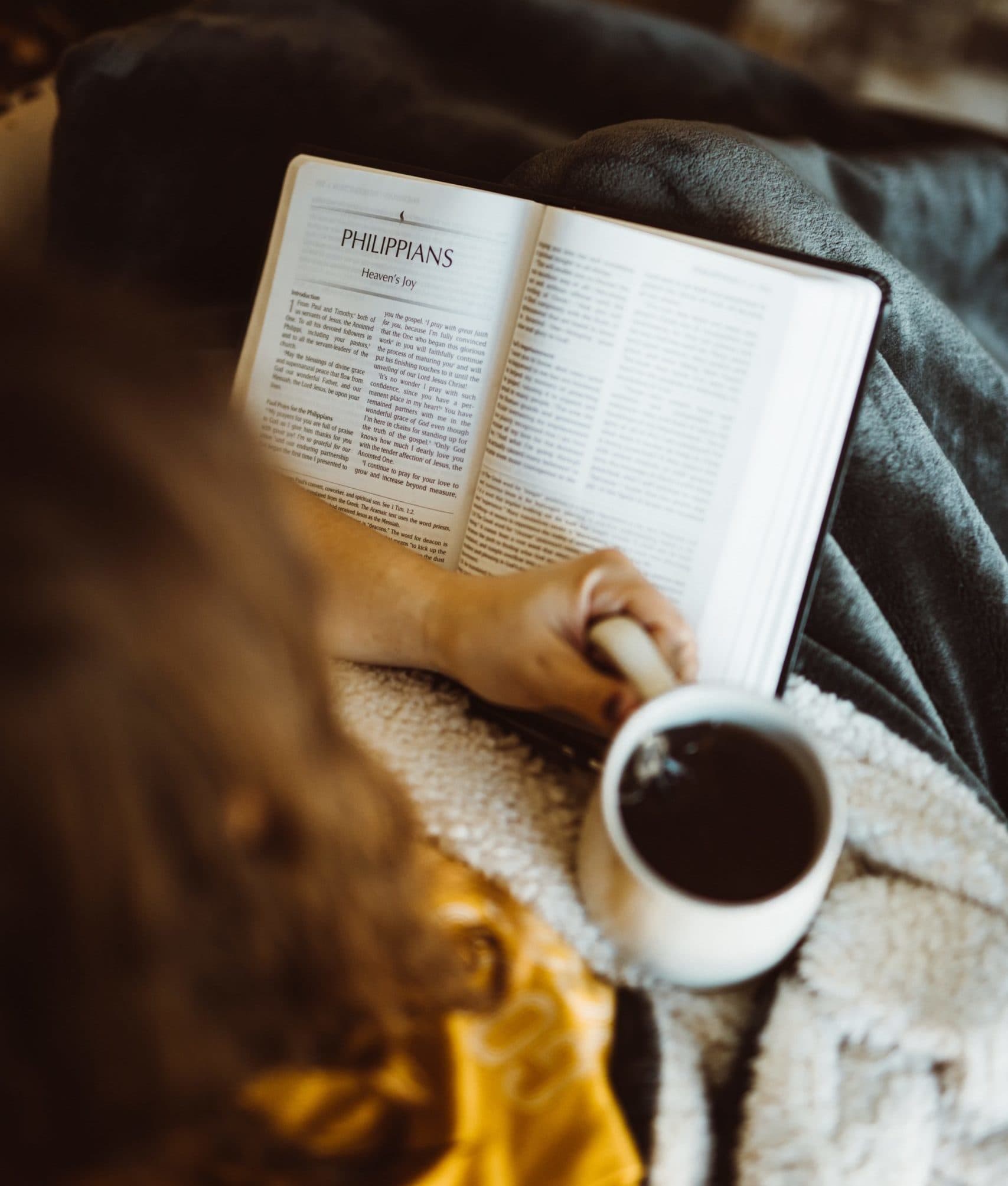 Person reading bible and drinking coffee
