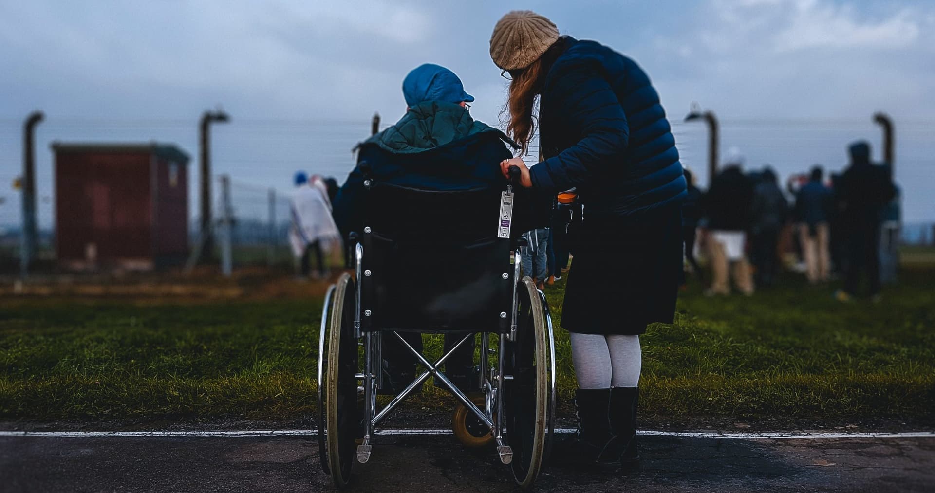 A woman in a wheelchair with a caregiver standing beside