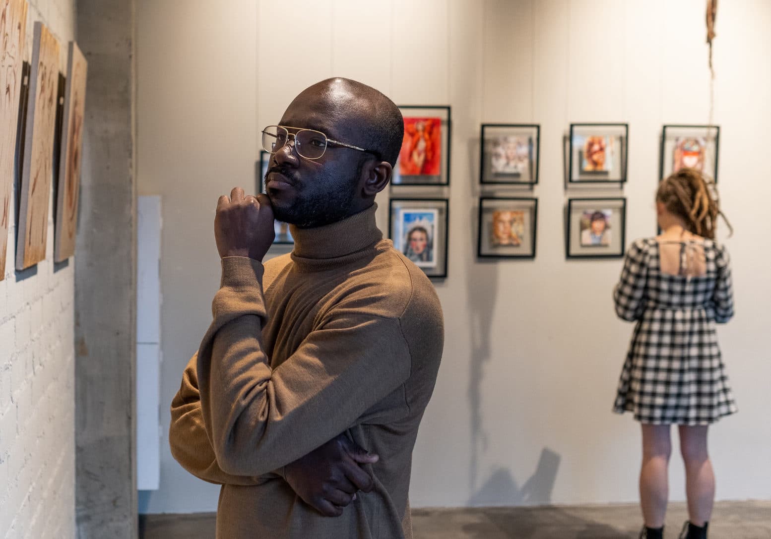 Person contemplatively reflecting on a painting in a gallery